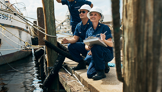 Two Coast Guard members at a dock taking notes