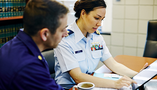 Two US Coast Guard members reading something on a tablet