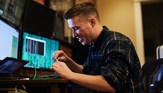 A Technician woring with wires sitting in front of a computer